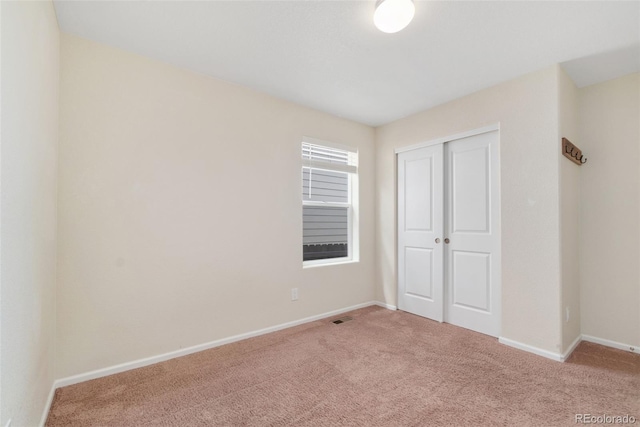 unfurnished bedroom with carpet, a closet, and baseboards