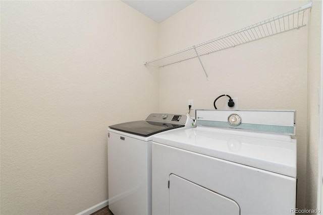 laundry area with independent washer and dryer and baseboards