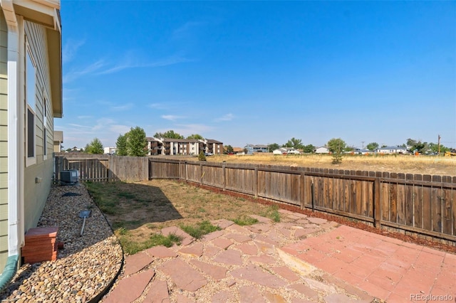 fenced backyard featuring a patio, central AC unit, and a residential view