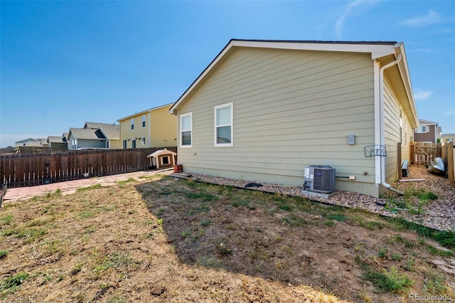 back of property with central AC and a fenced backyard