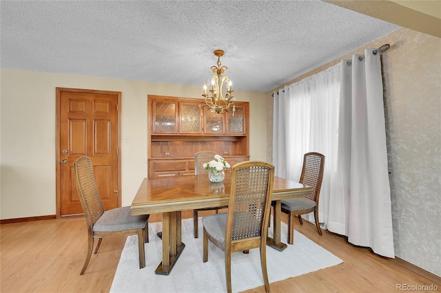 dining area with an inviting chandelier, light hardwood / wood-style flooring, and a textured ceiling