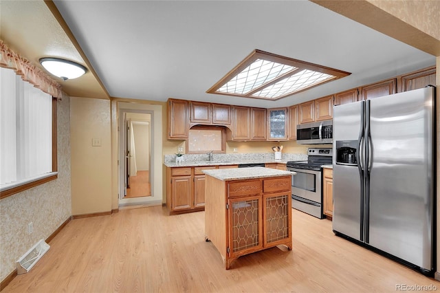 kitchen with sink, light hardwood / wood-style flooring, stainless steel appliances, and a kitchen island