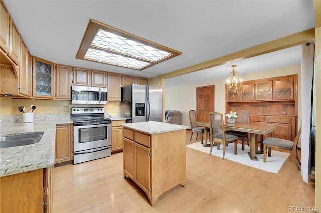 kitchen featuring a kitchen island, light stone countertops, appliances with stainless steel finishes, and light hardwood / wood-style flooring