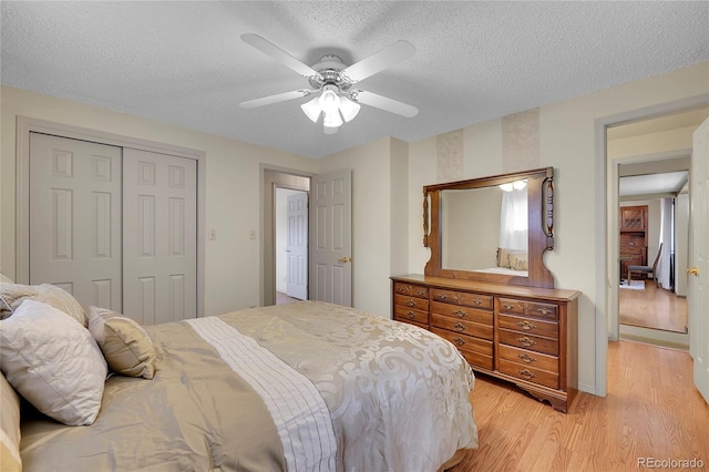 bedroom with ceiling fan, a textured ceiling, a closet, and light wood-type flooring