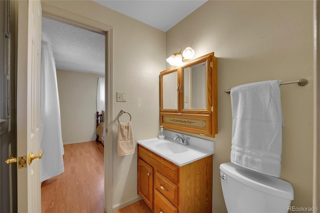 bathroom with vanity, hardwood / wood-style floors, toilet, and a textured ceiling