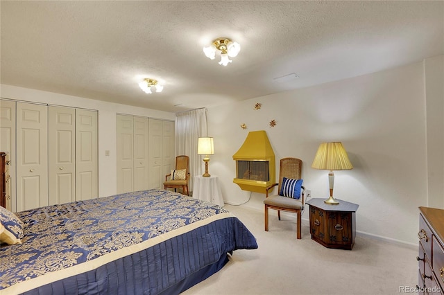 bedroom with light carpet, two closets, and a textured ceiling