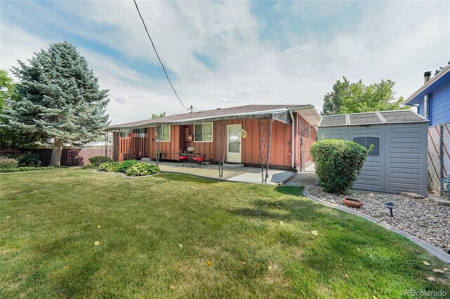 rear view of property featuring a storage shed, a yard, and a patio area