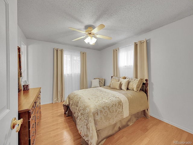 6769 W 70th Ave, Arvada, CO 80003 - bedroom featuring light wood-style floors, baseboards, a textured ceiling, and ceiling fan
