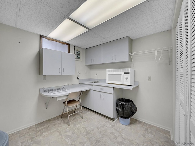 6769 W 70th Ave, Arvada, CO 80003 - kitchen with white microwave, a sink, a paneled ceiling, baseboards, and light countertops
