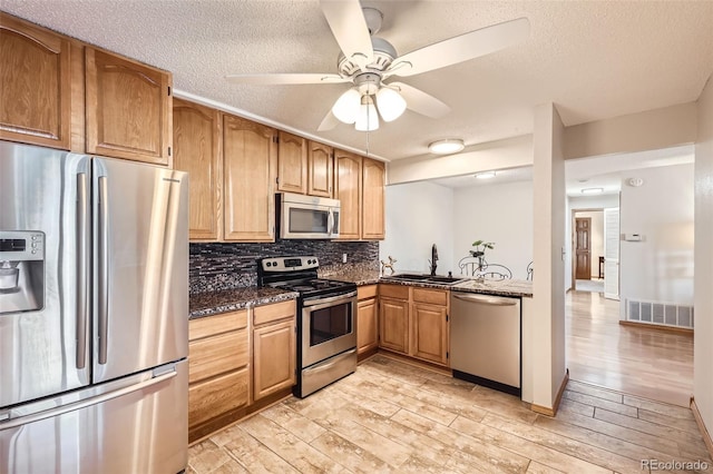 kitchen featuring dark stone countertops, light hardwood / wood-style flooring, stainless steel appliances, and sink