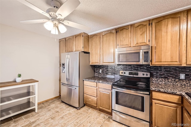 kitchen with ceiling fan, stainless steel appliances, light hardwood / wood-style flooring, backsplash, and dark stone countertops