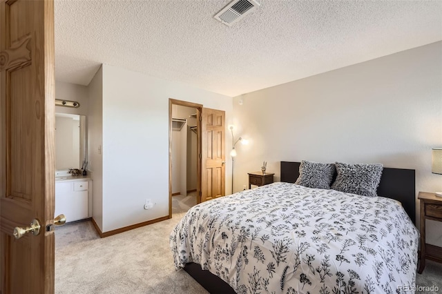 carpeted bedroom featuring a textured ceiling, a walk in closet, ensuite bathroom, and a closet