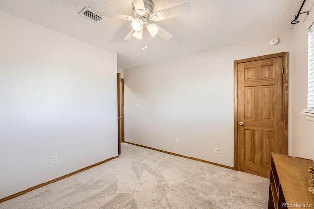 carpeted spare room with a textured ceiling and ceiling fan