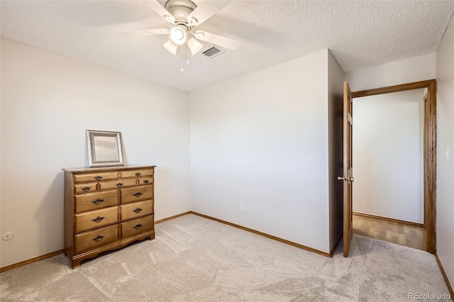 bedroom featuring ceiling fan, light colored carpet, and a textured ceiling