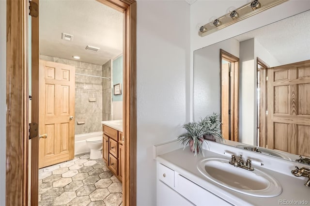 full bathroom with tile patterned floors, vanity, tiled shower / bath combo, and toilet