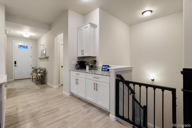 kitchen with light stone countertops, light wood-type flooring, and white cabinets