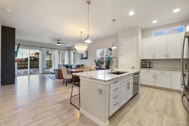 kitchen featuring sink, a center island with sink, appliances with stainless steel finishes, pendant lighting, and white cabinets