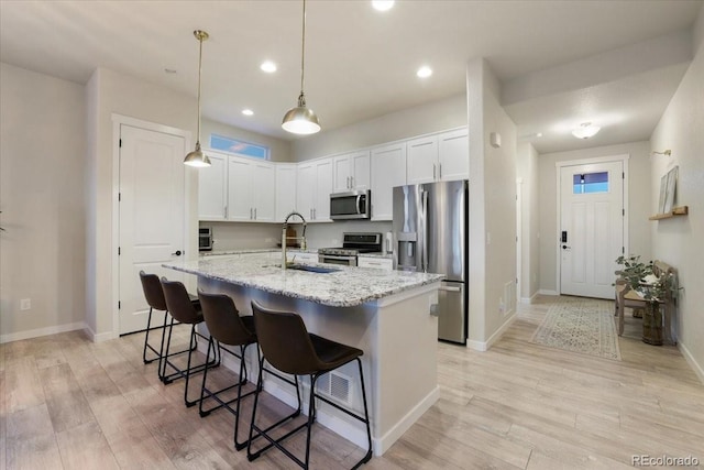 kitchen with stainless steel appliances, hanging light fixtures, sink, and white cabinets