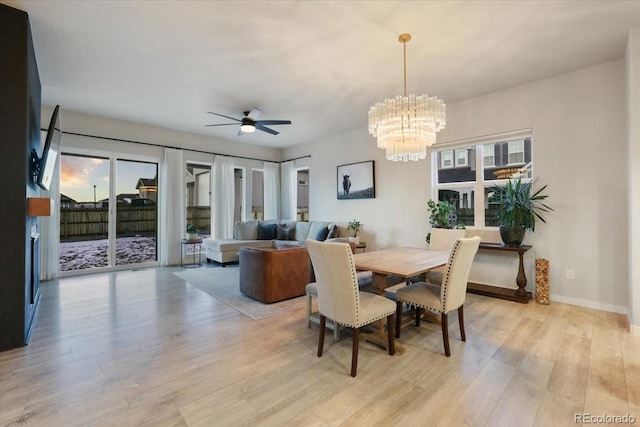 dining space featuring ceiling fan with notable chandelier and light hardwood / wood-style flooring