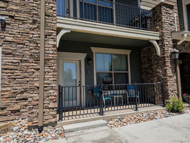 4612 Hahns Peak Dr Unit 102, Loveland, CO 80538 - doorway to property featuring stone siding, a balcony, and a porch