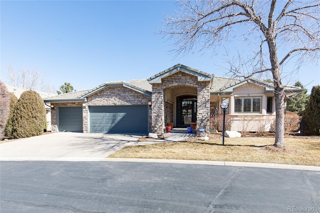 view of front facade featuring stone siding, concrete driveway, a tile roof, and an attached garage