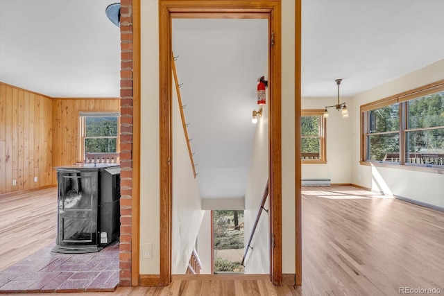 stairs with visible vents, baseboards, wood walls, wood finished floors, and a baseboard radiator