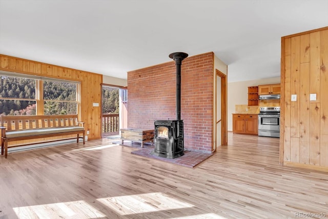 living room with wooden walls, light wood-type flooring, and a wood stove