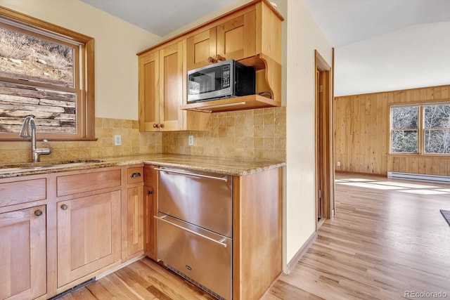 kitchen with decorative backsplash, stainless steel microwave, light wood finished floors, and a sink