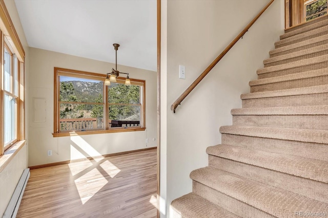 staircase featuring baseboard heating, baseboards, and wood finished floors