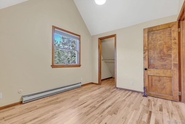 unfurnished bedroom with baseboards, a baseboard heating unit, light wood-style floors, and vaulted ceiling