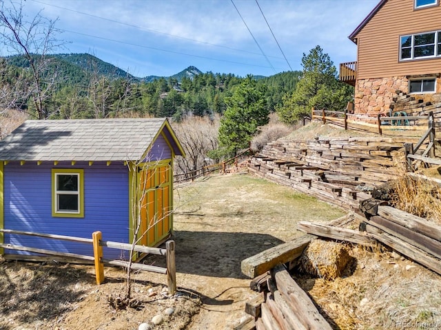 exterior space with a mountain view, a storage shed, an outdoor structure, and fence