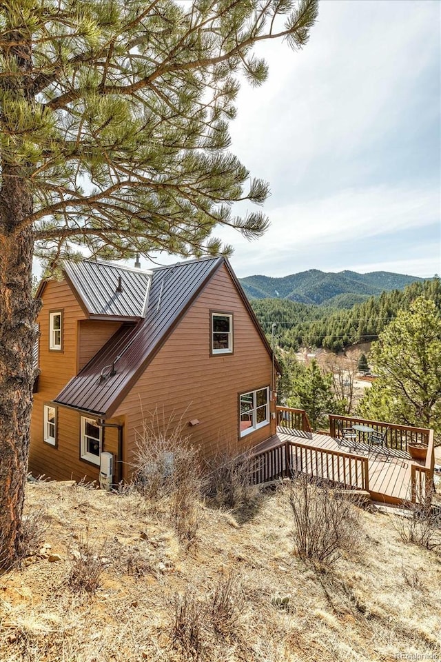 view of side of home with a standing seam roof, a deck with mountain view, and metal roof