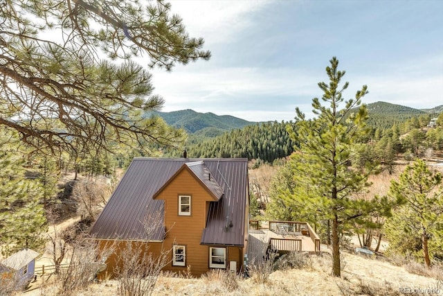 exterior space with a deck with mountain view, metal roof, and a forest view