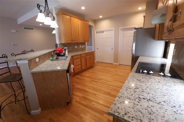 kitchen with light stone countertops, pendant lighting, tasteful backsplash, kitchen peninsula, and a breakfast bar