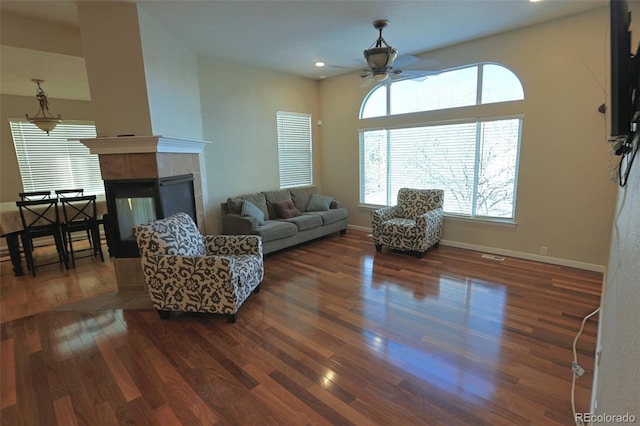 living room featuring ceiling fan, a tile fireplace, and dark hardwood / wood-style floors