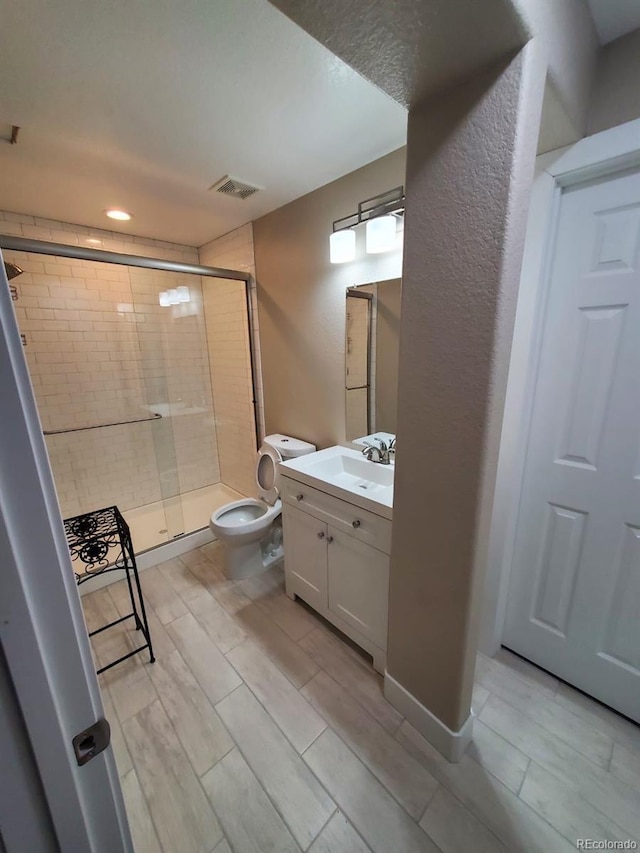 bathroom featuring toilet, walk in shower, and vanity