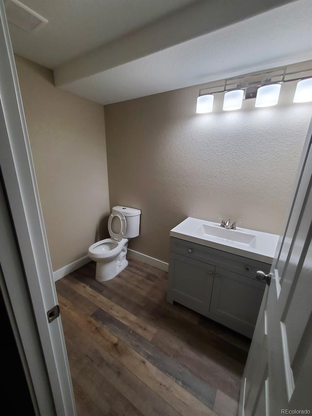 bathroom with hardwood / wood-style flooring, toilet, and vanity