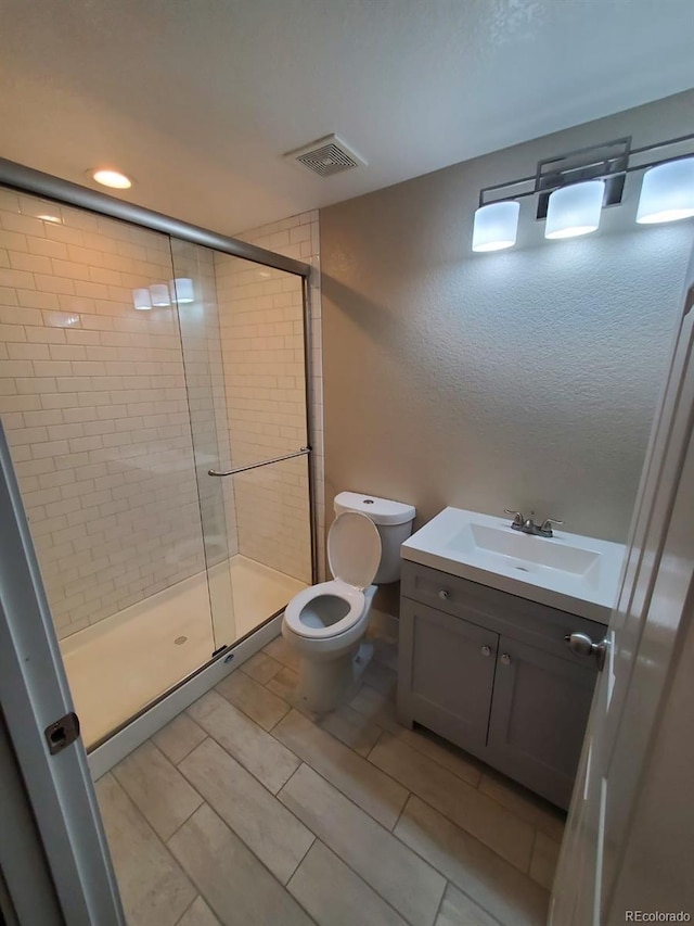 bathroom featuring toilet, an enclosed shower, and vanity