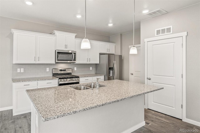 kitchen featuring pendant lighting, hardwood / wood-style floors, a kitchen island with sink, white cabinets, and appliances with stainless steel finishes