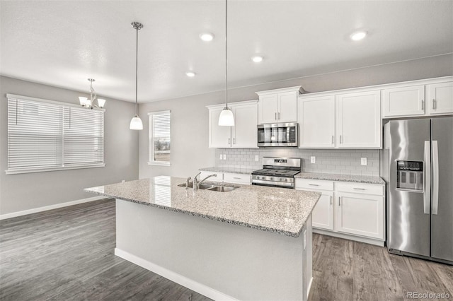 kitchen featuring white cabinets, sink, an island with sink, decorative light fixtures, and stainless steel appliances