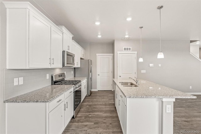 kitchen with appliances with stainless steel finishes, sink, decorative light fixtures, dark hardwood / wood-style floors, and white cabinetry