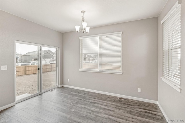 spare room with a chandelier and wood-type flooring