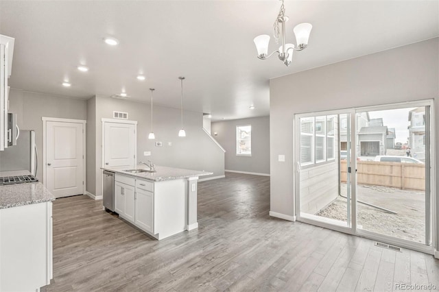 kitchen featuring sink, stainless steel appliances, light hardwood / wood-style floors, decorative light fixtures, and white cabinets