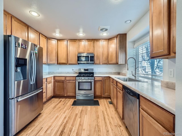 kitchen with sink, light wood-type flooring, and appliances with stainless steel finishes