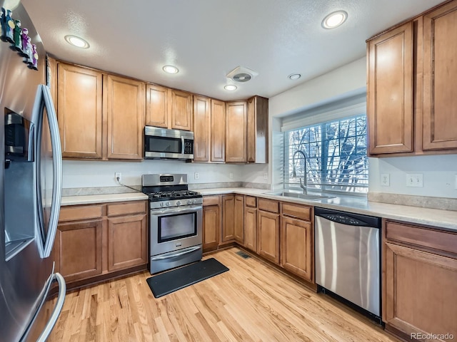 kitchen featuring stainless steel appliances, light hardwood / wood-style flooring, and sink