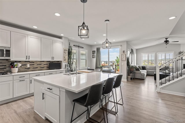 16486 W 94th Dr, Arvada, CO 80007 - kitchen with white cabinets, recessed lighting, backsplash, stainless steel microwave, and light countertops