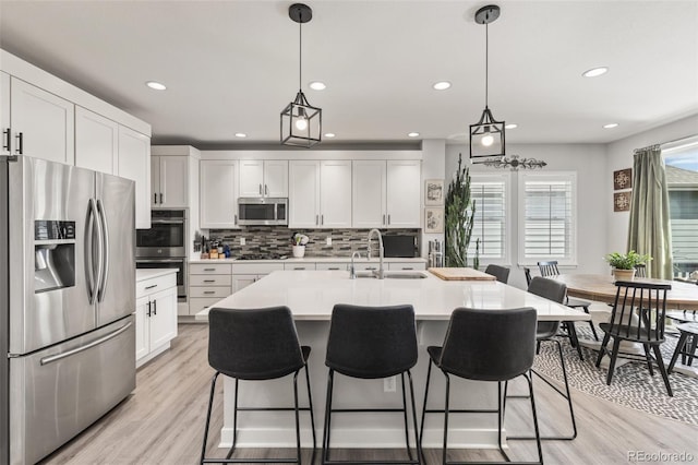 16486 W 94th Dr, Arvada, CO 80007 - kitchen featuring appliances with stainless steel finishes, backsplash, a kitchen breakfast bar, light countertops, and light wood-style floors
