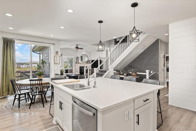 16486 W 94th Dr, Arvada, CO 80007 - kitchen with stainless steel dishwasher, a ceiling fan, open floor plan, recessed lighting, and light wood-type flooring