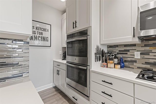 16486 W 94th Dr, Arvada, CO 80007 - kitchen featuring appliances with stainless steel finishes, backsplash, light countertops, white cabinets, and light wood-style flooring