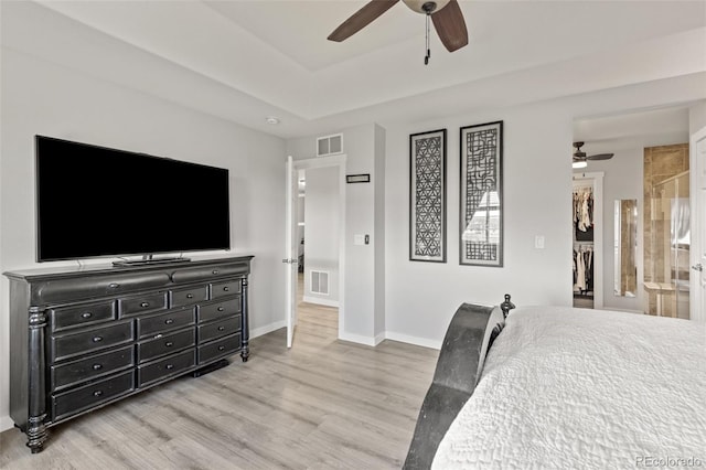 16486 W 94th Dr, Arvada, CO 80007 - bedroom featuring wood finished floors, a spacious closet, a tray ceiling, a ceiling fan, and a closet